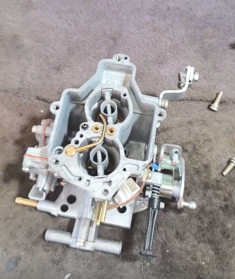 An open carburetor with its internal parts and linkages visible.